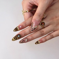 Ongles à presser en acrylique de luxe motif léopard, base rose nude, ligne métallique dorée, strass irisés, forme amande, ongles élégants et audacieux