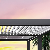 Pergola à lames orientables avec rideaux transparents et table brasero pour terrasse en bois dans la cour au crépuscule