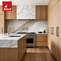 Cuisine moderne en placage de chêne blanc, définie par des veines de marbre spectaculaires, avec une île sculpturale en demi-cascade et une armoire de rangement en panneaux de marbre.