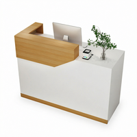 Bureau d'accueil moderne blanc avec accent en grain de bois, comptoir surélevé et poste de travail en L pour hall d'accueil de bureau