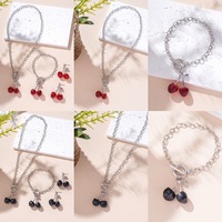 Parure de bijoux élégante pour femme, motif cerise rouge et noire vintage, comprenant boucles d'oreilles clous à pompon, collier, bracelet chaîne cordon et chaîne de clavicule OT