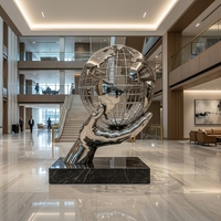 Grande sculpture de globe terrestre creux en acier inoxydable poli miroir, en forme de main tenant un globe, pour l'aménagement paysager des places universitaires