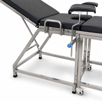 Table d'examen gynécologique en acier inoxydable pour centre médical avec supports de jambes rembourrés et structure stable