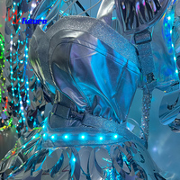 Ensemble de vêtements LED avec plumes argentées brillantes, jupe courte et aile, modèle de piste.