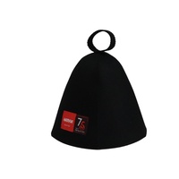 Un gorro de sauna negro de pura lana que hereda el legado en su frente mientras el calor rinde homenaje a los setenta y cinco años de maestría.
