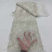Tissu en dentelle de haute couture lourdement perlé avec franges en boucle motif feuille d'argent sur tulle ivoire pour robe de mariée et robe de soirée