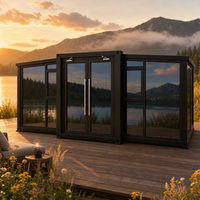 Casa Contenedor Plegable Expandible con Marco Negro y Vidrio Azul, con Puertas Dobles, para Glamping en la Orilla del Lago
