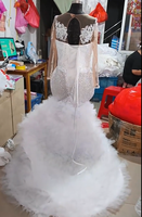 Robe de mariée sirène de luxe blanche perlée 2026 avec encolure illusion transparente, manches longues et traîne volumineuse à volants