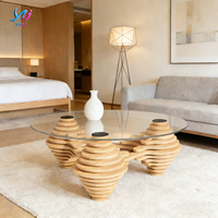 Table basse moderne et écologique au design unique avec plateau en verre transparent et pieds en bois empilés artistiquement pour salon, espace de réception à domicile