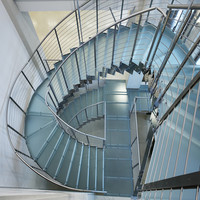 Escalier flottant contemporain courbé avec marches en bois de chêne et rampes en métal noir pour maisons modernes