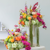 Farbenfrohe Tropische Seiden-Kunstblumenarrangements: Pink-orangefarbene Rosen, Calla-Lilien, hängende Amaranth-Blumen als Hochzeits-Tischdekoration