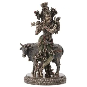 힌두교 신 크리슈나의 수지 동상과 거룩한 소의 청동 동상