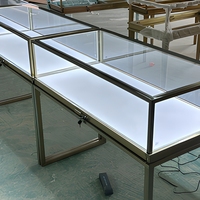 Vitrine à bijoux autoportante en verre avec cadre noir, pieds hauts et éclairage LED pour les bijouteries professionnelles