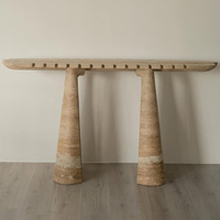 Table console en marbre travertin beige, plateau allongé de forme planche de surf, bord dentelé, quatre pieds coniques effilés, table d'entrée