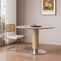 Table moderne avec plateau en pierre frittée, colonne en placage de bois et base en métal poli