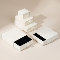 Boîte à bijoux sur mesure en blanc ivoire avec ruban de tirage pour une marque d'élite et une boutique de détail sophistiquée