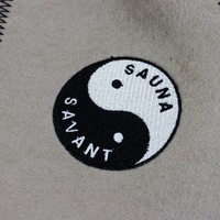 Un chapeau de sauna en pure laine beige qui équilibre la vapeur avec un emblème Yin Yang qui profite de chaque côté de la chaleur