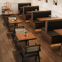 Ensemble de mobilier pour café-restaurant : tables carrées en bois avec base métallique, chaises en rotin à dossier en bois et banquette.