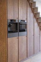 Armoire de rangement sous escalier sur mesure avec four encastré et penderie dissimulée, design en panneaux de bois