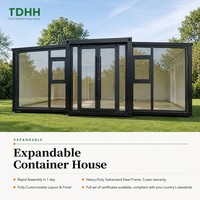 Maison conteneur extensible TDHH avec structure noire, mur en verre pleine hauteur et porte d'entrée à double vitrage