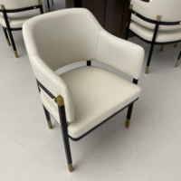 Chaise de salle à manger moderne avec dossier en cuir, revêtement blanc crème et structure en métal noir avec accents dorés pour salle à manger