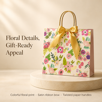 Sac cadeau en papier imprimé floral avec nœud en satin doré et poignées en corde torsadée pour l'emballage de cadeaux de détail
