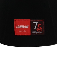 Un gorro de sauna negro de pura lana que hereda el legado en su frente mientras el calor rinde homenaje a los setenta y cinco años de maestría.