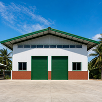 Atelier préfabriqué en acier à toit à pignon vert, avec pignon profond, aérations à persiennes, porte enroulable et base en briques