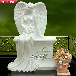 墓石に座っている天使の翼と屋外の庭の白い大理石の墓石