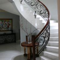 Escalier incurvé élégant en fer forgé sur mesure pour le hall d'entrée de la villa ferronnerie artistique et marches en bois