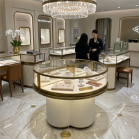 Vitrine à bijoux ronde personnalisée avec base en forme de trèfle, verre incurvé et cadre doré pour les boutiques de bijoux haut de gamme