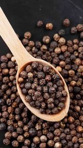 Granos de pimienta negra en cuchara de madera sobre fondo negro para condimentar en la cocina - Product Image 3