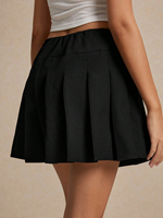 Jupe mini plissée taille haute noire pour femme avec revers contrastant, détail boutonné, style preppy, coupe trapèze