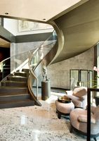 L'élément ultime pour le hall d'entrée : Escalier courbé sur mesure avec éclairage intégré et finitions métalliques raffinées