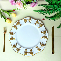 Assiettes de présentation en or blanc avec nœud papillon, bord ondulé et décor en relief, pour la mise en table de banquets de mariage