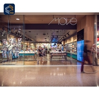 Comptoir d'exposition mobile contemporain en verre pour smartphones, avec îlot de démonstration, espace de paiement, accessoires muraux, signalétique de marque et éclairage sécurisé