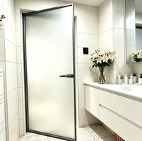 Porte de salle de bain à battants en verre dépoli, cadre en métal noir, poignée à barre, ouverture vers l'intérieur, porte de séparation intérieure moderne pour l'intimité