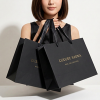 Sacs shopping en papier noir mat élégants avec logo personnalisé, impression dorée à chaud, et poignées en ruban pour l'emballage de perruques en boutique