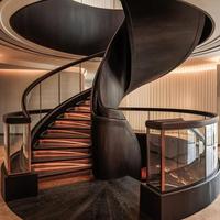 Escalier courbé pour hôtel haut de gamme avec finition en pierre luxueuse et système de rampe sur mesure