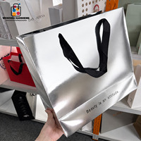 Sac en carton holographique argenté brillant de luxe avec logo noir personnalisé imprimé et poignée en ruban pour boutiques et commerces de détail