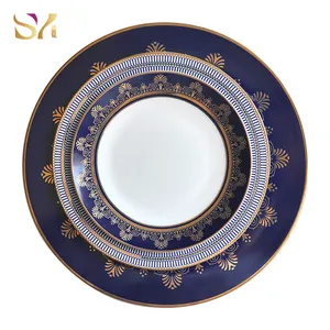 Service de vaisselle en céramique de luxe en gros, assiettes en porcelaine osseuse à bordure dorée au design bleu et rouge pour le dîner de mariage