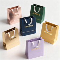 Sac en papier d'art de luxe avec poignée, logo personnalisé en relief et imprimé à l'écran pour un emballage haut de gamme de vêtements et de chaussettes
