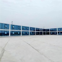 Grande structure de bureau modulaire préfabriquée en conteneurs en forme de L sur deux étages, avec façade en verre bleu, fenêtres à auvent, maison mobile et portable