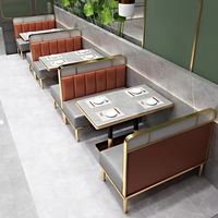 Banquette de restaurant confortable et légère en cuir gris à dossier haut, base de table basse dorée et chaise de restaurant blanche