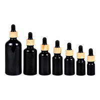 Flacon compte-gouttes cylindrique en verre noir mat personnalisé avec logo, bouchon doré/noir, pour huiles essentielles, sérums et cosmétiques – Vente en gros