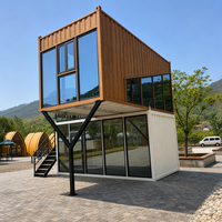 Maison préfabriquée contemporaine en conteneur à deux étages, avec toit en pente imitation bois, mur entièrement vitré et design cantilever.