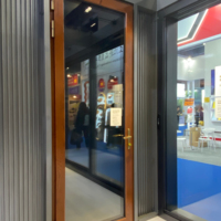Una puerta abatible de madera maciza francesa moderna con un marco de aleación de aluminio y una puerta de vidrio exterior, delineando un ambiente cálido en el hogar