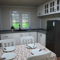 Maison conteneur extensible à bordure blanche 20 pieds, toit à pignon, couleur crème, 2 chambres, fenêtres à grille, porche, terrasse, cabane entièrement équipée