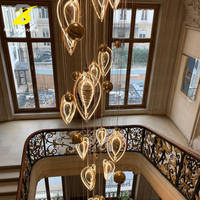 Lustre suspendu LED en forme de goutte d'eau avec accents dorés pour grandes escalinades et espaces à plafond haut – Éclairage de luxe personnalisable