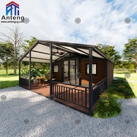 Maison conteneur pliable extensible en bois foncé avec toit à pignon et terrasse, spacieuse et privée, pour famille ou invités